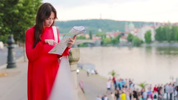 Giovane donna felice con una mappa della città in Europa sfondo famoso ponte. Viaggio donna turistica con mappa all'aperto durante le vacanze in Europa . — Video Stock
