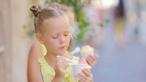 Приваблива маленька дівчинка, що їсть морозиво на вулиці влітку. Милий хлопчина, що насолоджується справжньою італійською желато біля Гелатерії в Римі. — стокове відео