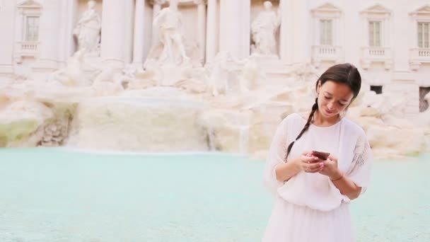 Ung kvinna med smart telefon på varm dag utomhus i europeiska staden nära berömda Fontana di Trevi — Stockvideo