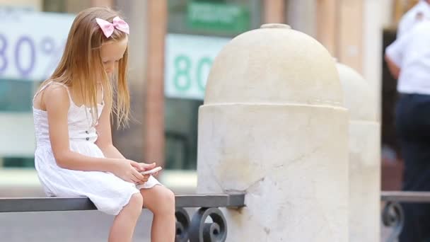 Красивая маленькая девочка с сотовым телефоном в теплый день на открытом воздухе в европейском городе недалеко от знаменитого Фонтана Треви — стоковое видео