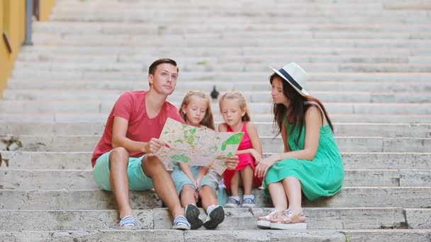 Vacaciones familiares en Europa. Padres e hijos con mapa turístico buscando en las atracciones . — Vídeo de stock