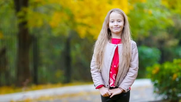 Portret van een schattig meisje in de herfst kijkend naar de camera en glimlachend — Stockvideo