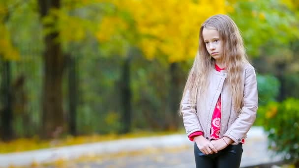 Πορτρέτο του λυπημένου κοριτσιού το φθινόπωρο κοιτάζοντας την κάμερα και χαμογελώντας — Αρχείο Βίντεο