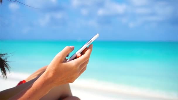 Νεαρή γυναίκα χρησιμοποιεί τηλέφωνο κατά τη διάρκεια τροπικών διακοπών στην παραλία. Κοντινό πλάνο κινητό smartphone. — Αρχείο Βίντεο