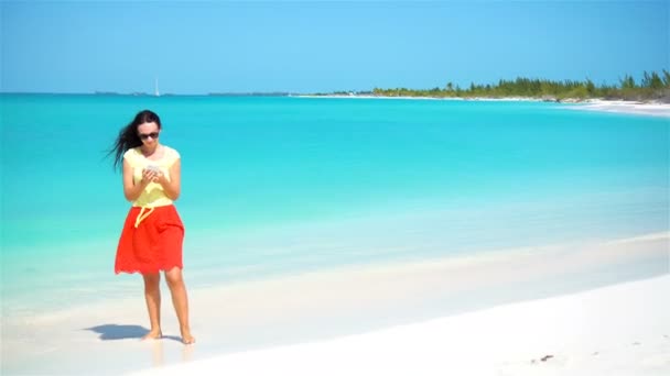 Junge Frauen telefonieren während ihres Urlaubs am tropischen Strand. Touristin nutzt Handy. — Stockvideo