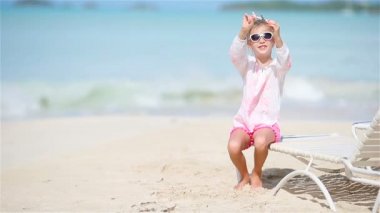 Beyaz kumlu sahilde elinde oyuncak uçakla küçük mutlu bir kız. Çocuk kumsalda oyuncakla oynuyor.