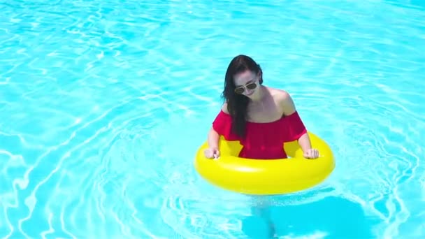 Красивая молодая женщина отдыхает в бассейне. Девушка в открытом бассейне в роскошном отеле с надувным резиновым кругом — стоковое видео