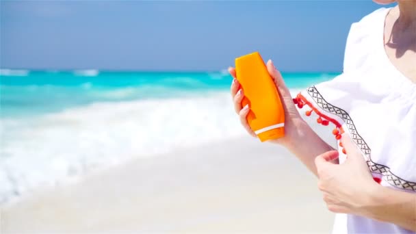 Protector solar mujer que aplica loción bronceadora mostrando botella. Hermosa mujer feliz sonriente con crema bronceadora en contenedor de plástico en la playa durante las vacaciones de verano . — Vídeos de Stock
