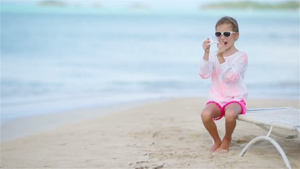 Счастливая маленькая девочка с игрушечным самолетом в руках на белом пляже — стоковое видео