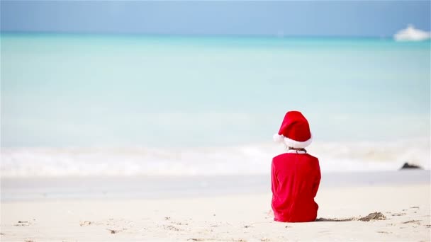 Vissza kilátás imádnivaló lány karácsonyi kalap a strandon a karácsonyi vakáció — Stock videók