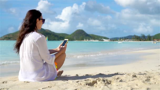 Jonge vrouw liggend op wit zand en praten door haar telefoon — Stockvideo