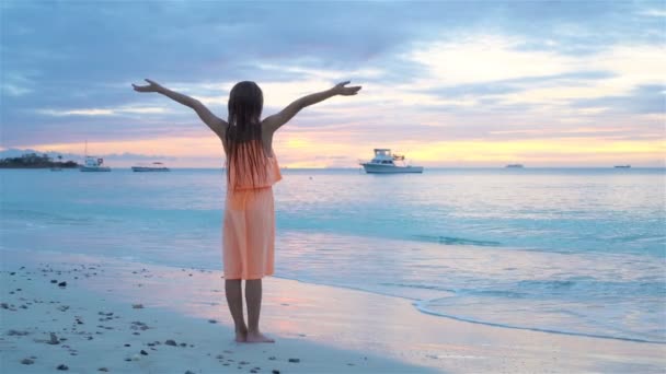 Adorable niña feliz caminando en la playa blanca al atardecer. MOCIÓN LENTA — Vídeos de Stock