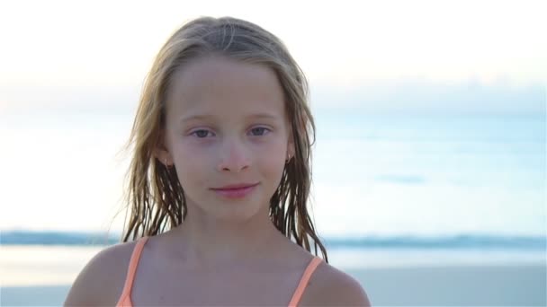 照片上的小女孩看着相机，微笑着背景音乐，美丽的天空和大海. — 图库视频影像