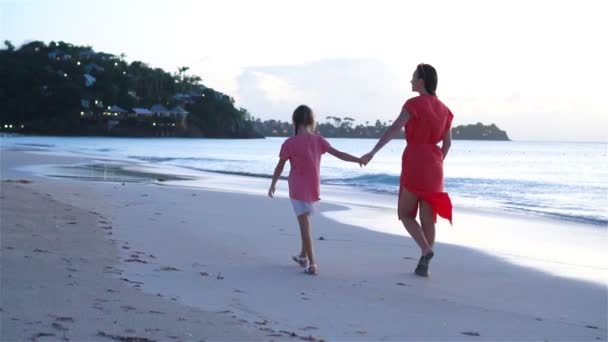 Young beautiful mother and her adorable little daughter have fun at tropical beach