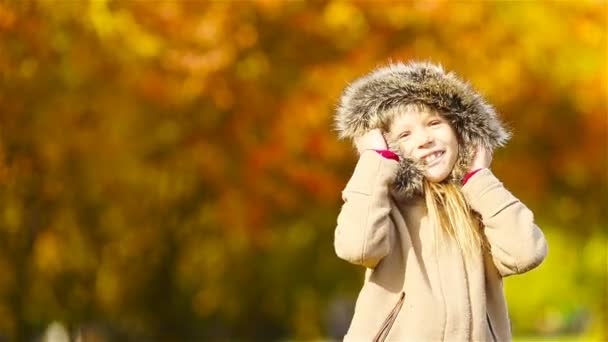 Portrait of adorable little girl outdoors at beautiful warm day with yellow leaf in fall — Stock Video