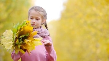 Güzel bir sonbahar gününde, sarı ve turuncu yapraklı sevimli küçük bir kızın portresi.