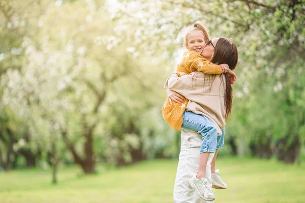 Familie van moeder en dochter in bloeiende kersentuin — Stockfoto