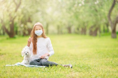 Parkta virüsü önlemek için köpekli küçük bir kız koruyucu maske takıyor.