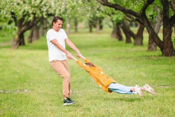 Family of father and daughter in blooming cherry garden — Stock Photo, Image