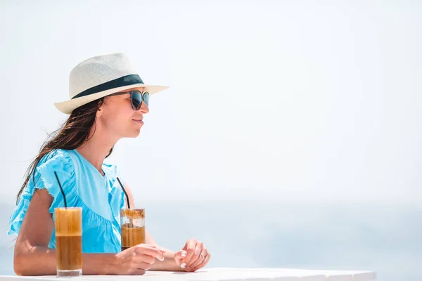 Młoda kobieta pije zimną kawę ciesząc się widokiem na morze. — Zdjęcie stockowe