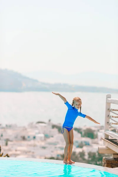 Adorable little girl on the edge of outdoor swimming pool — Stock Photo, Image