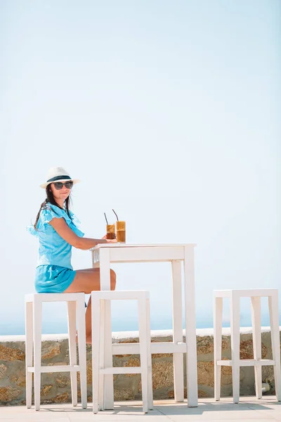 Νεαρή γυναίκα πίνει κρύο καφέ απολαμβάνοντας θέα στη θάλασσα. — Φωτογραφία Αρχείου
