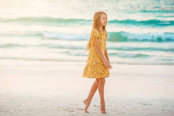 Очаровательная счастливая маленькая девочка на белом пляже на закате. — стоковое фото