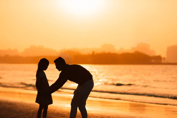 Κοριτσάκι και μπαμπάς σιλουέτα στο ηλιοβασίλεμα στην παραλία — Φωτογραφία Αρχείου