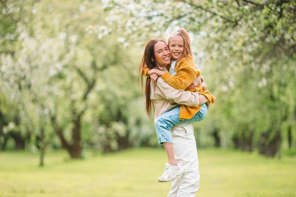 Family of mother and daughter in blooming cherry garden — Stock Photo, Image