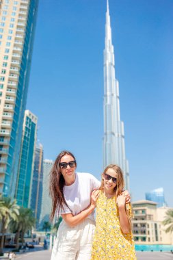 Arka planda gökdelenlerle Dubai 'de yürüyen mutlu bir aile..