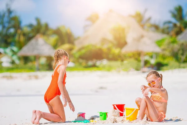 Malé šťastné zábavné dívky mají spoustu zábavy na tropické pláži hrát spolu. — Stock fotografie