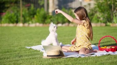 Parkta köpek yavrusuyla oynayan gülümseyen küçük kız.