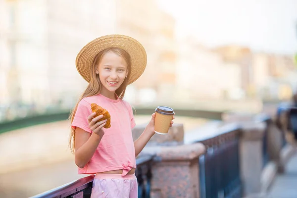 Mujer con un croissant y café al aire libre en el paseo marítimo —  Fotos de Stock