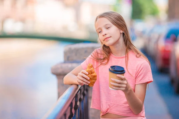 Mujer con un croissant y café al aire libre en el paseo marítimo — Foto de Stock