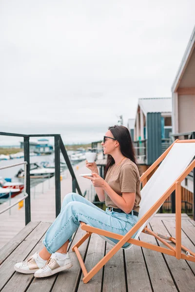 Junge Frau trinkt heißen Kaffee und genießt den Blick auf den Strand. — Stockfoto