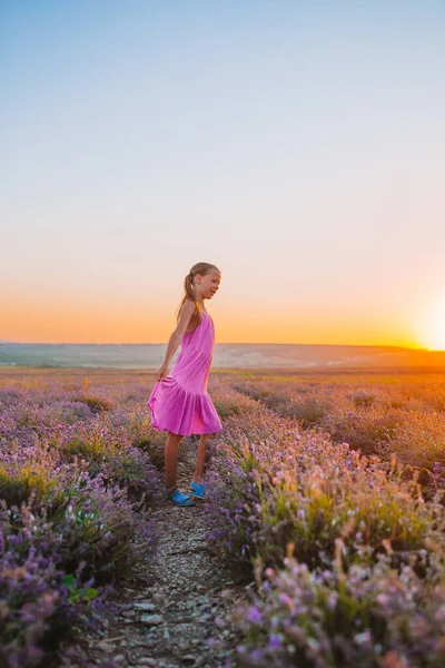 Frau in Lavendelblütenfeld bei Sonnenuntergang in weißem Kleid und Hut — Stockfoto