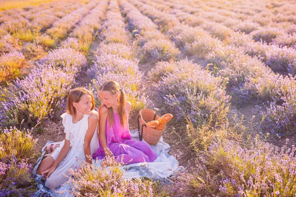 Crianças no campo de flores de lavanda ao pôr do sol em vestido branco e chapéu — Fotografia de Stock