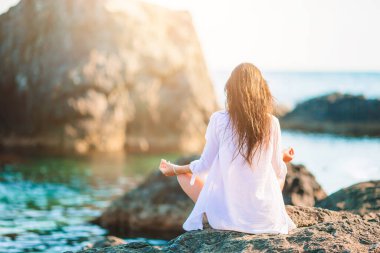 Sahilde yoga yapan genç ve güzel bir kadın.