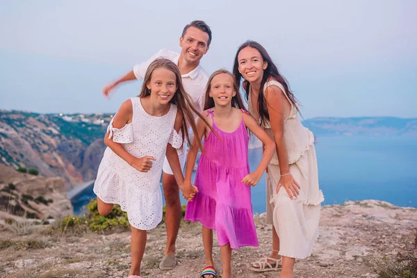 Mutlu dört kişilik aile gün batımında dağlarda yürüyor.