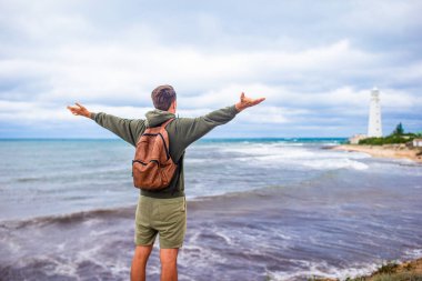 İki kişilik adam deniz fenerine doğru yürür.