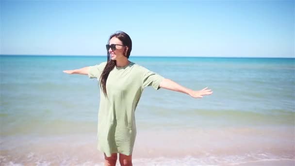 Νεαρή όμορφη γυναίκα διασκεδάζει στην τροπική ακτή. Ευτυχισμένο κορίτσι φόντο το γαλάζιο του ουρανού και τιρκουάζ νερό στη θάλασσα — Αρχείο Βίντεο