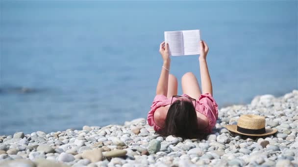 Молодая женщина читает книгу во время тропического белого пляжа — стоковое видео