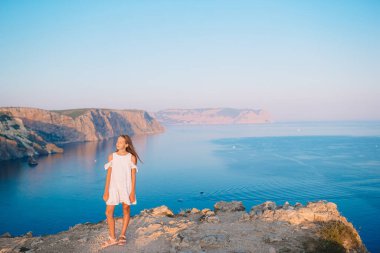 Dağın tepesinde gün batımından önce vadinin tadını çıkaran küçük bir kız.