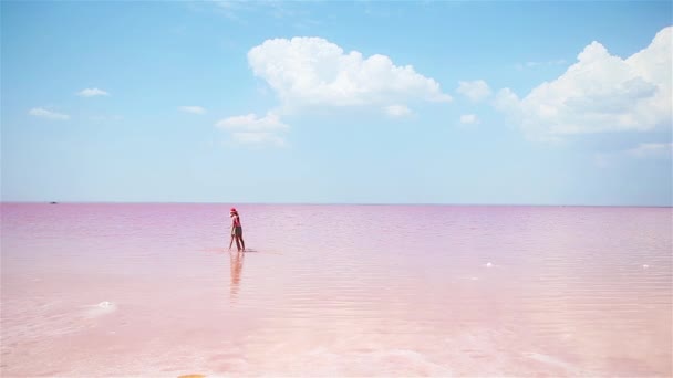 Niñas niñas caminan en un lago de sal rosa en un día soleado de verano . — Vídeos de Stock