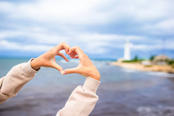 Female hands in the form of heart against the lighthouse — Stock Photo, Image