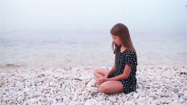 Маленькая девочка на тропическом белом пляже строит замок из песка — стоковое видео