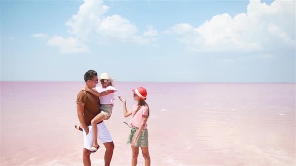 Családi séta egy rózsaszín sós tavon egy napos nyári napon. — Stock videók