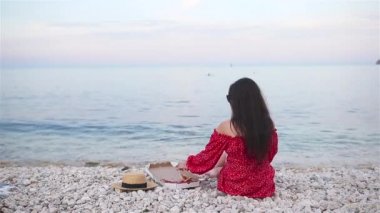 Kadın plajda pizzayla piknik yapıyor.