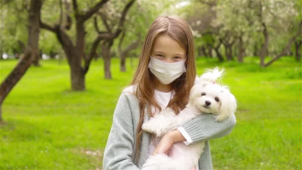公園の屋外でウイルスを防ぐために保護医療マスクを身に着けている犬と女の子 — ストック動画