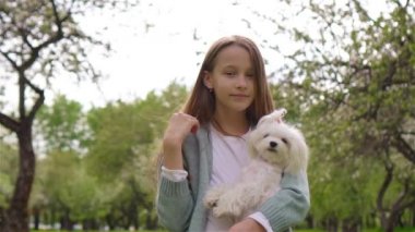 Parkta köpek yavrusuyla oynayan gülümseyen küçük kız.